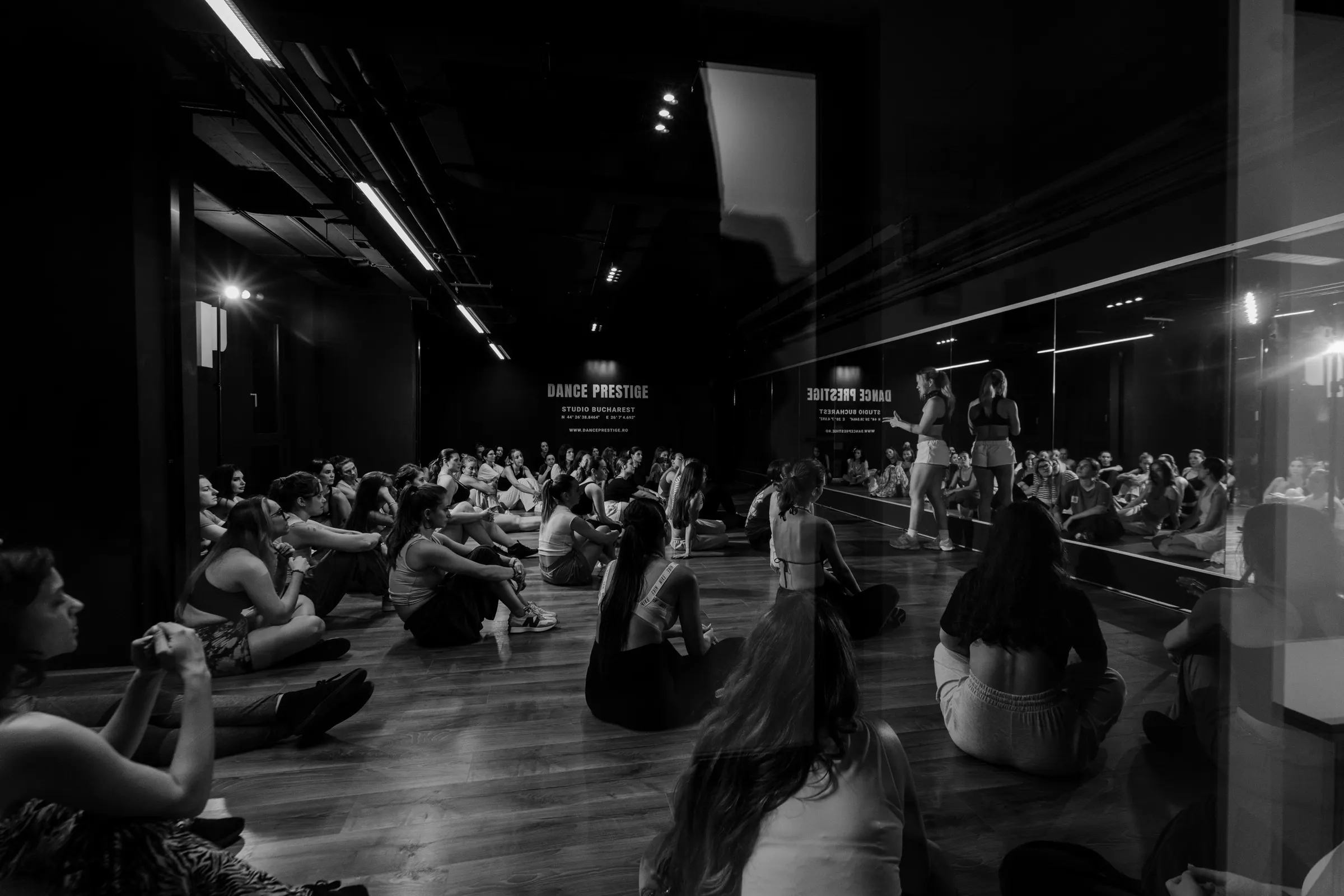 The group seated on the floor, listening, black and white